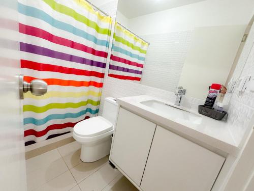y baño con aseo y cortina de ducha de arco iris. en Apartamento exclusivo a 70 metros de san Isidro, en Lima