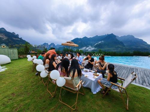 a group of people sitting around a table by the water at XMAN Sunrise Peaks Resort--Free Pick-up in Zhangjiajie