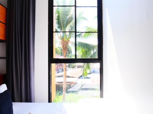 a window with a view of a palm tree at Book a Bed Poshtel - SHA Plus in Phuket Town