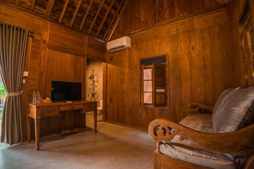a room with a desk and a bed and a television at Umadhatu Resort by Amerta in Tabanan