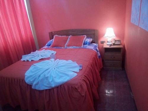 a red bedroom with a bed with two pillows on it at Hotel Bethania in Oruro