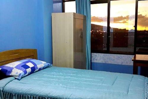 a blue bedroom with a bed and a window at Hotel Bethania in Oruro