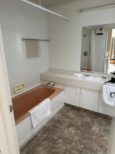 a bathroom with a tub and a sink and a mirror at Helensborough Motor Inn in Balclutha