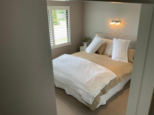 a bedroom with a large bed with white sheets and pillows at Pegasus Amberley, Entire Studio in Waikuku