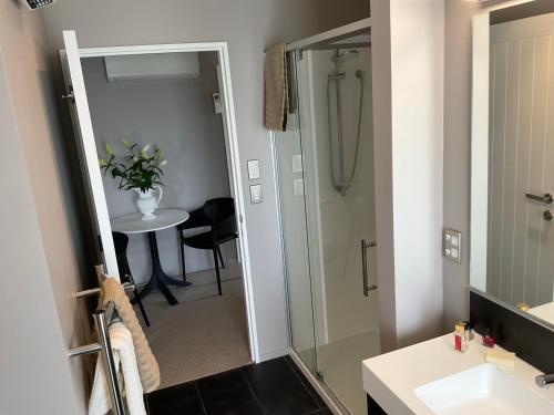 a bathroom with a shower and a sink and a table at Pegasus Amberley, Entire Studio in Waikuku
