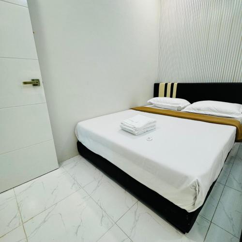 a white bedroom with a bed with white sheets at Rayyaz Inn in Kuala Terengganu