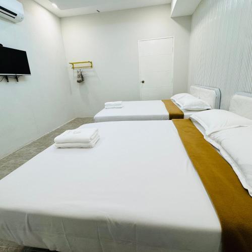 two beds in a white room with a tv at Rayyaz Inn in Kuala Terengganu