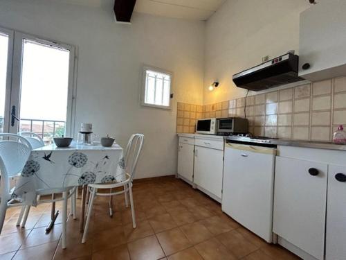 - une cuisine avec une table, une table et des chaises dans l'établissement Sainte-Maxime : Appartement lumineux 2 pièces avec parking dans résidence calme - FR-1-226-536, à Sainte-Maxime