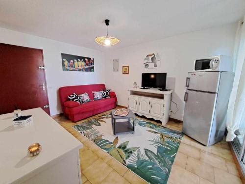 - un salon avec un réfrigérateur et un canapé rouge dans l'établissement Appartement cosy 2 pièces - jardin privé, accès direct plage, animaux acceptés ! - FR-1-326-801, à Marseillan