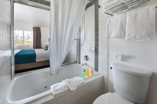 a bathroom with a tub and a toilet and a bed at The Marina Inn in Anacortes