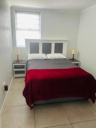 a bedroom with a large bed with a red blanket at 24 on Elizabeth in East London