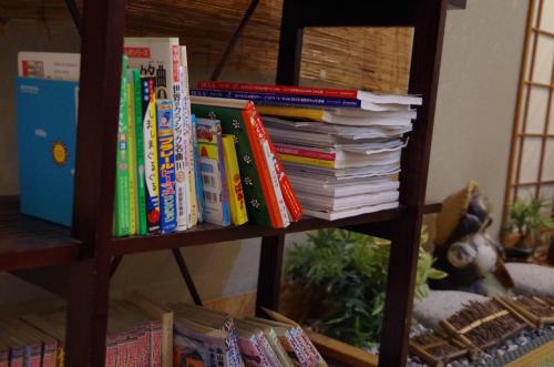 a book shelf with a stack of books at あじ彩の宿小浜荘 in Toba