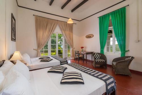 2 Betten in einem Zimmer mit grünen Vorhängen in der Unterkunft Kudaoya Bungalow in Rattota