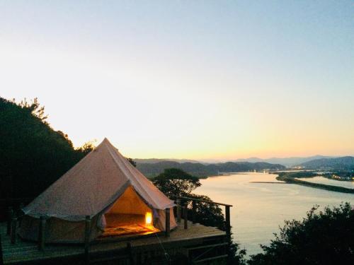 a tent with a fire in it next to a river at Yamamizuki in Shimanto