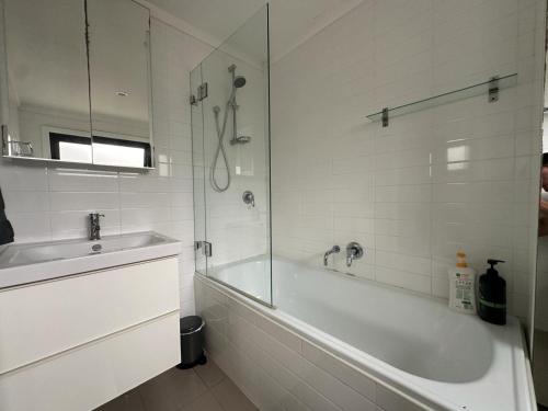 Baño blanco con bañera y lavamanos en Dynamic 2 Bedroom home close to city buzz Darling St 2 E-Bikes Included en Sídney
