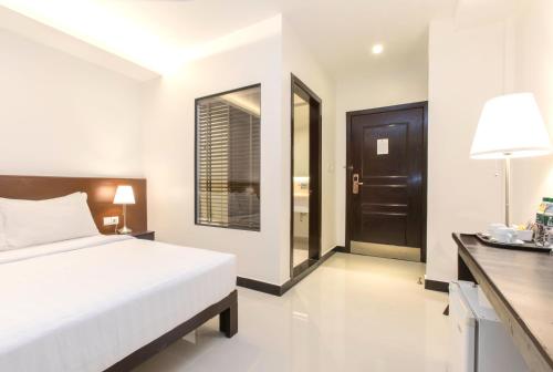 um quarto com uma cama, uma escrivaninha e uma janela em Cambodian Country Club em Phnom Penh