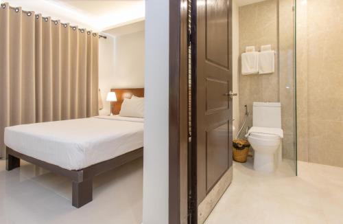 a bedroom with a bed and a bathroom with a toilet at Cambodian Country Club in Phnom Penh