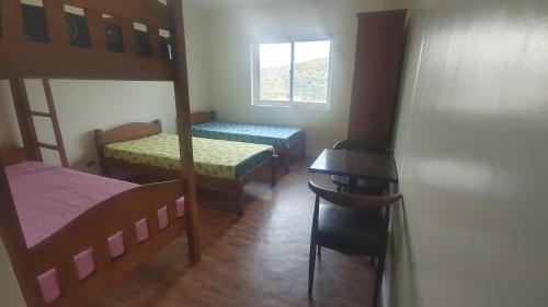 a bedroom with bunk beds and a table and a desk at Baguio BELL Staycation in Baguio