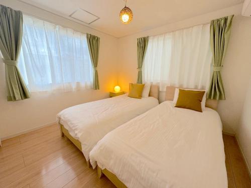 a bedroom with two beds and a window at グランディオーソ沖縄ヴィラ恩納1 in Onna