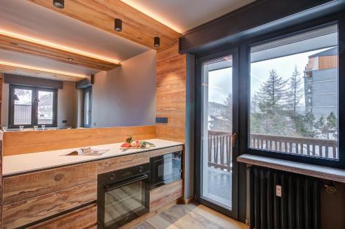 eine Küche mit einem Waschbecken und einem großen Fenster in der Unterkunft Simona LuxuryApartment Few Steps From Ski - Happy Rentals in Sestriere