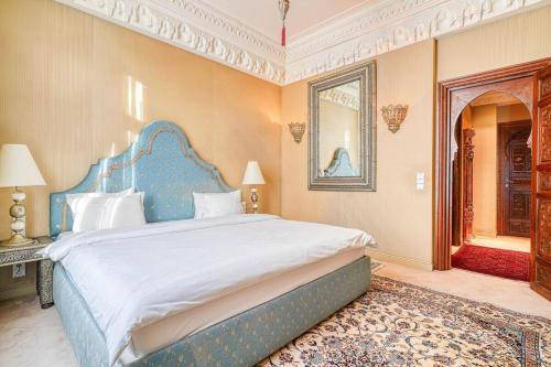 une chambre avec un grand lit avec une tête de lit bleue dans l'établissement Marrakech Suite Champs Elysees, à Paris