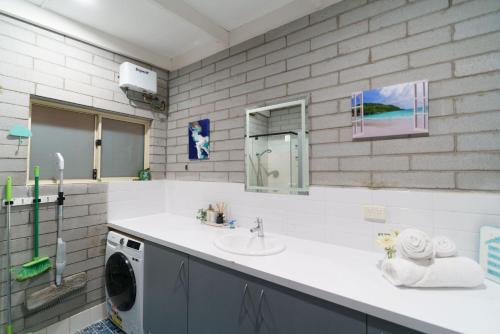 a bathroom with a sink and a washing machine at OCEA84 - Quinns Beach Shack: Ocean Views in Quinns Rocks
