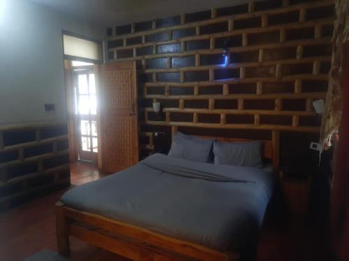 a bed in a room with a brick wall at manorma cottage in Dharamshala