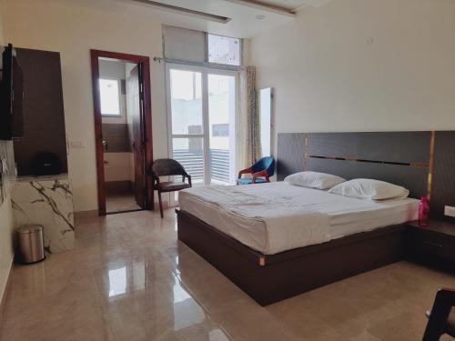 ein Schlafzimmer mit einem großen Bett und einem großen Fenster in der Unterkunft C T Heights Inn in Bharatpur