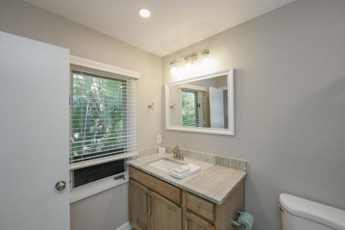 a bathroom with a sink and a mirror and a toilet at La Buena Vida - Bright Beachy Canal Front Steps to Beach PoolSpa Dock Beach Gear Dogs OK in Anna Maria