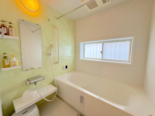 a bathroom with a tub and a toilet and a sink at グランディオーソ沖縄ヴィラ恩納1 in Onna