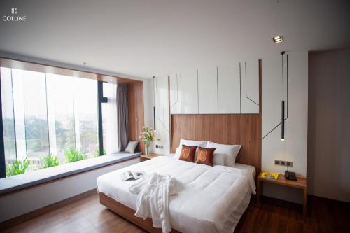 a bedroom with a large bed and a large window at Colline Dalat in Da Lat