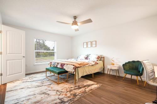 a bedroom with a bed and two chairs and a ceiling fan at Sunny Palm Coast: 3BR Harmony in Palm Coast