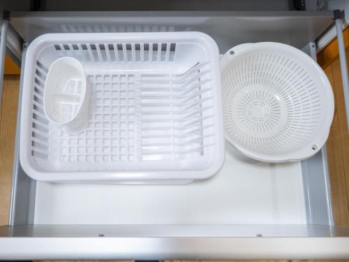 an open refrigerator with two white baskets and a fan at Tabino Hotel Villa Miyakojima in Miyako Island
