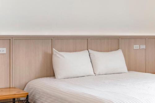 a bed with white pillows and a wooden head board at Taitung Spring Homestay B&B in Taitung City