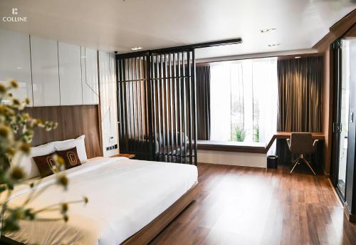 a bedroom with a large white bed and a desk at Colline Dalat in Da Lat