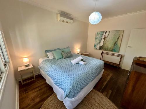 1 dormitorio con 1 cama con edredón azul en Barefoot Beach Cottage, en Geographe