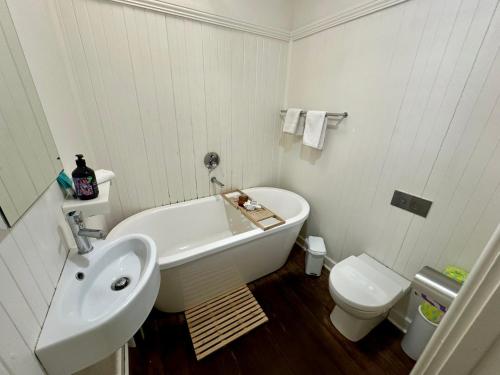 a bathroom with a sink and a tub and a toilet at Barefoot Beach Cottage in Geographe