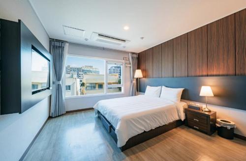 a bedroom with a large bed and a window at Jin Motel in Seogwipo