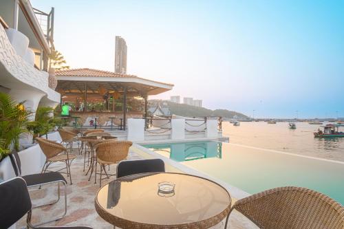 eine Terrasse mit Tischen und Stühlen neben dem Wasser in der Unterkunft Windy Inn Hotel Pattaya in Pattaya South