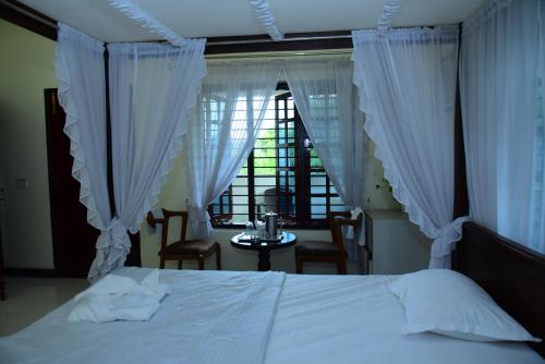 a bedroom with a white bed and a window at Serenity Cottage Luxury Homestay Virajpet in Virajpet