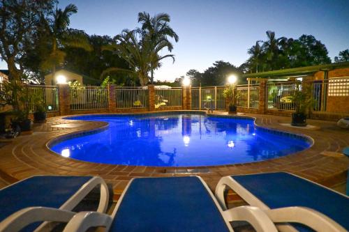 a large swimming pool with blue water in a yard at Glen Villa Resort in Byron Bay