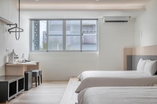a bedroom with two beds and a desk and a window at Taitung Spring Homestay B&B in Taitung City