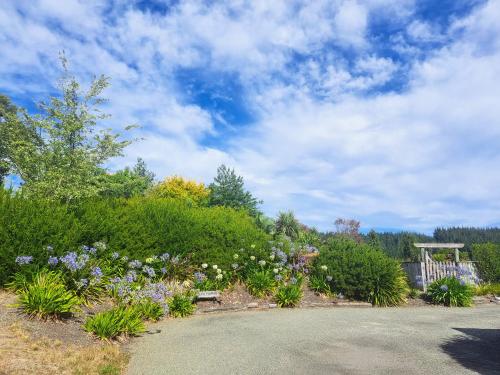 a garden with flowers and a gazebo at Golden Hills Farm Cottage in Nelson