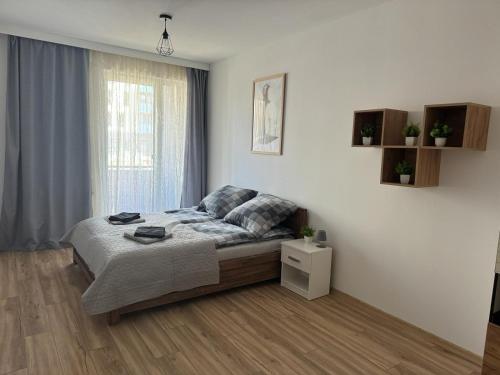 een witte slaapkamer met een bed en een raam bij Kotlina Kłodzka - Apartament na Letniej in Kłodzko