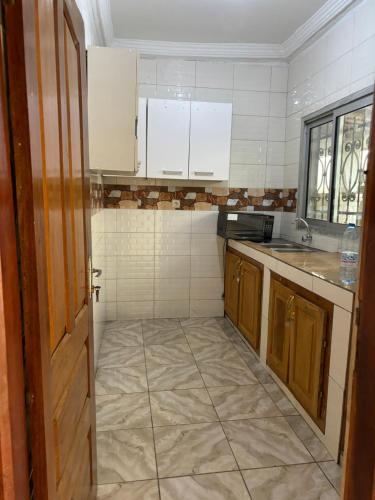 uma cozinha com armários brancos e piso em azulejo em Eden Meadows Estate (Dr. John) em Limbe