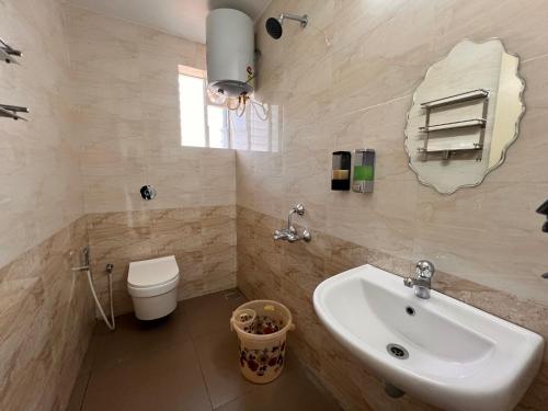 a bathroom with a sink and a toilet and a mirror at Nirvana Stay, Spacious Fully furnished 2bhk apartment in Mangalore, Full AC for Family in Mangalore