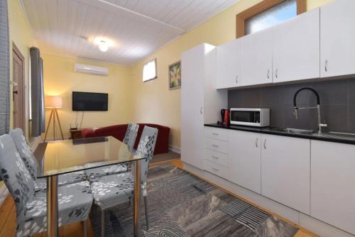 eine Küche mit einem Glastisch und weißen Schränken in der Unterkunft The Mess and Barracks in Ararat