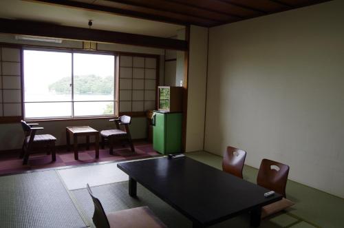 a room with a table and chairs and a refrigerator at あじ彩の宿小浜荘 in Toba