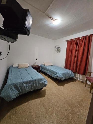 2 camas en una habitación con TV en la pared en Casa Don Sofanor en Neuquén