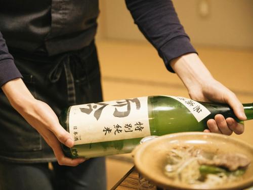 a person is holding a bottle of wine at あじ彩の宿小浜荘 in Toba